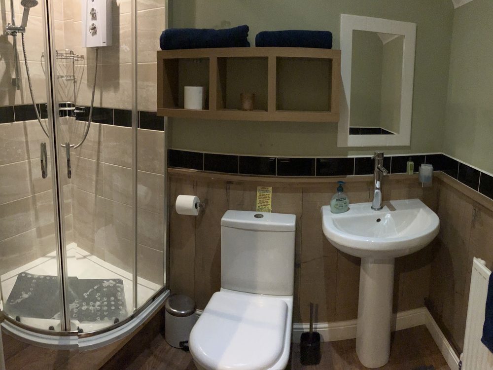 An en-suite shower room with a corner shower, basin and folded towels.